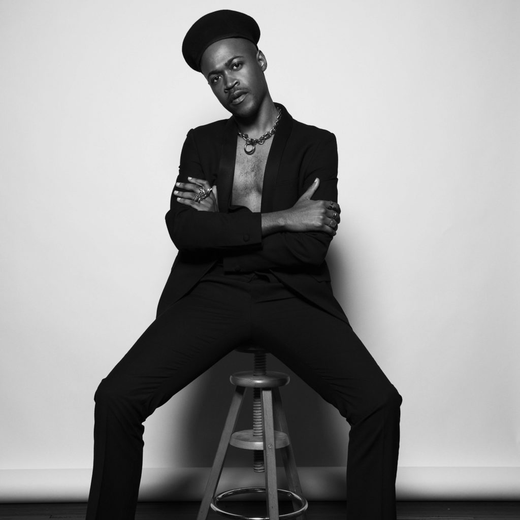 VAM Founder Vincent Martell sitting on a stool in a all black with a beret, black and white photo